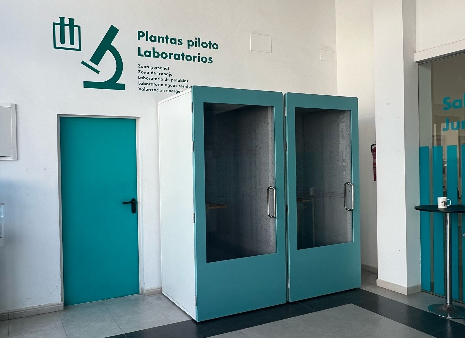 Cabinas acústicas turquesa integradas en un espacio de laboratorio con diseño corporativo.